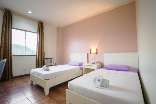 a hotel room with two beds and a window at The Inns Bacolod in Bacolod