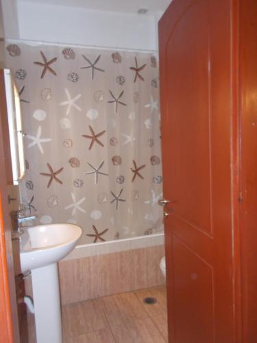 a bathroom with a sink and a shower curtain at Διαμέρισμα τεσσάρων ατόμων in Filiatra