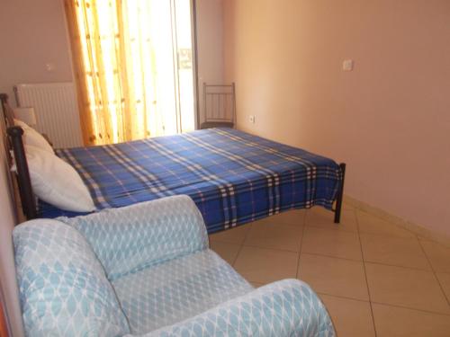 a bedroom with a bed and a couch and a chair at Διαμέρισμα τεσσάρων ατόμων in Filiatra