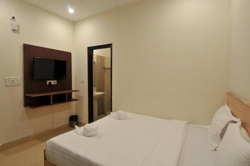 a bedroom with a white bed and a flat screen tv at Eva Hotel in Zirakpur