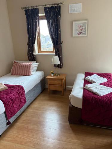 a bedroom with two beds and a window and a table at Luxury Town House-Apartment Carrick-on-shannon in Carrick on Shannon