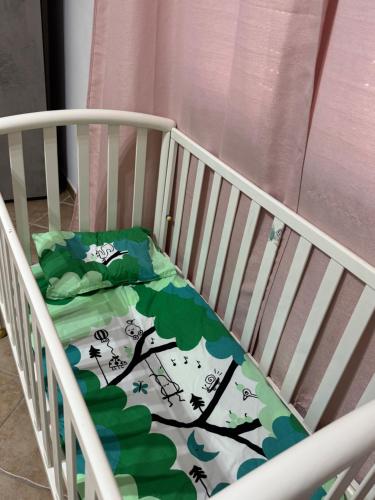 a crib with a blanket on it with a tree and birds at Casa via veneto in Carbonia