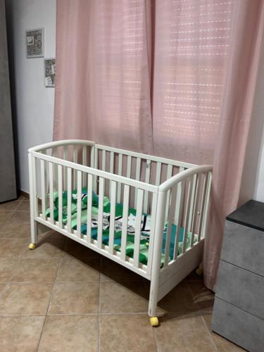 a white crib in front of a pink curtain at Casa via veneto in Carbonia