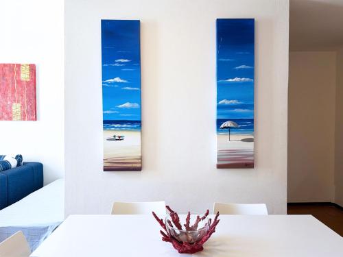 a dining room with three paintings of the beach at Appartamenti Napoleone al Poggio - ArgonautiVacanze in Poggio