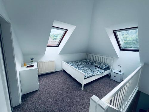 a small bedroom with a bed and two windows at Apart Aurum B&M in Jáchymov