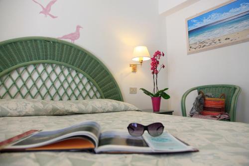 a bed with a book and sunglasses on it at Eco Hotel Montemerlo in Fetovaia