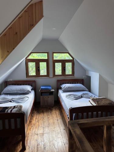two beds in a attic room with two windows at Shpia e Mikut Guesthouse in Theth