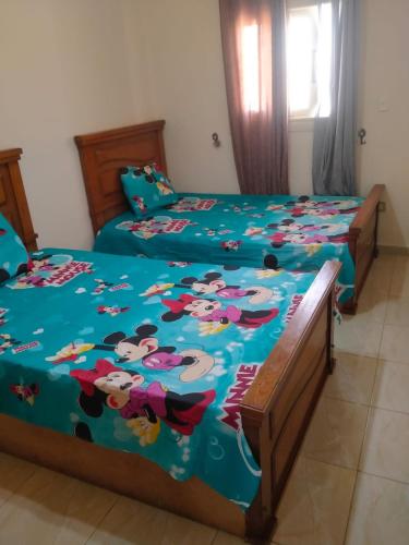 a bedroom with two beds with mickey mouse sheets at Qasr Diana in Marsa Matruh