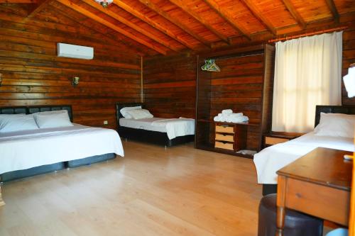 a bedroom with two beds and a wooden wall at Angels Garden Hotel in Olympos