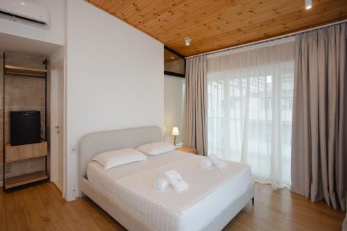 a bedroom with a white bed and a large window at Trevi Hotel & Restorant, Shengjin in Shëngjin