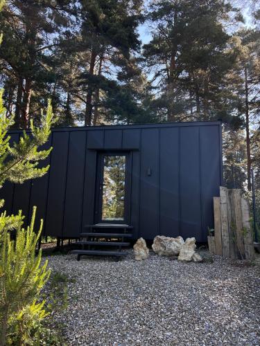 a black house in the woods with trees at Connect Cabin - Bungalow Brasov, jacuzzi & forest view in Purcăreni