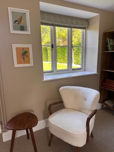 a chair and a table in a room with a window at Hinton Hayloft in Hinton in the Hedges