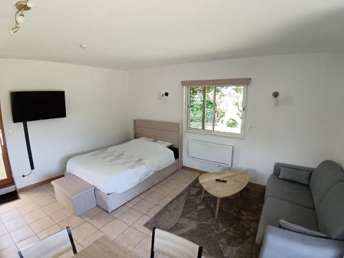 a bedroom with a bed and a couch and a tv at L'annexe in Gouy