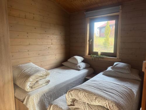 two twin beds in a room with a window at Domki Nad Satwem Mazury D2 in Mrągowo