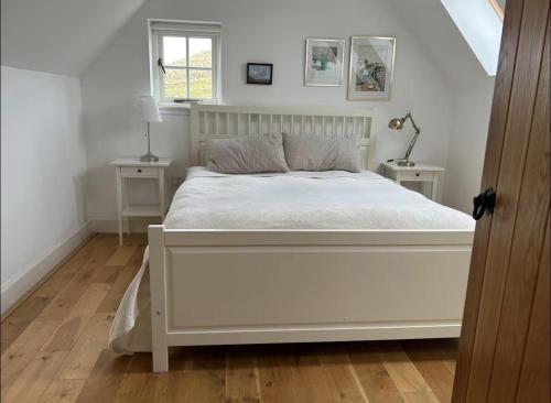 a white bed in a room with two tables at Harris Cuckoo Cottage in Luskentyre