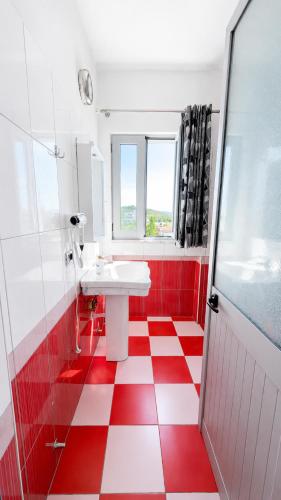 a bathroom with a red and white checkered floor at HOTEL SARDA in Vau i Dejës