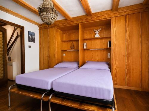 a bedroom with two beds in a wooden room at Bijou Alpina Surlej in Silvaplana