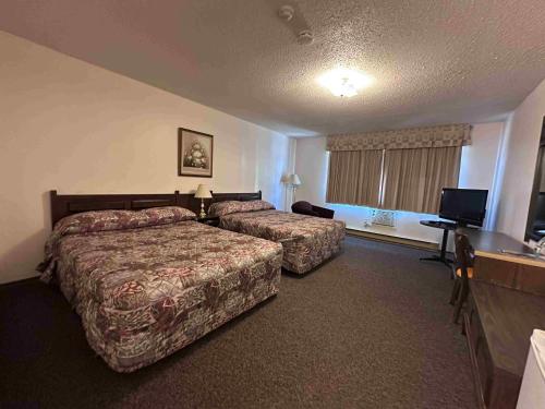a hotel room with two beds and a flat screen tv at Auberge Eldo Inn in Blind River