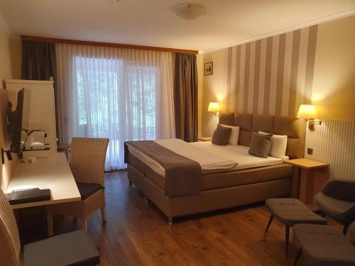 a hotel room with a large bed and a desk at Hotel Garni Eichhornkobel in Faßberg