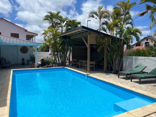 a pool in front of a house with palm trees at Coco Banana in Baie-Mahault