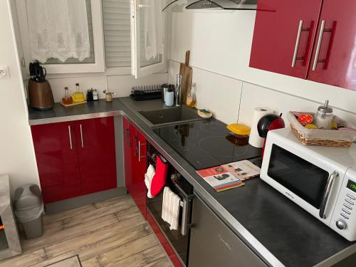 a small kitchen with red cabinets and a microwave at Centre Granville in Granville