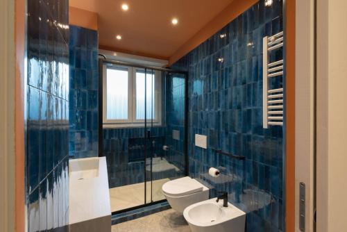 a bathroom with blue tiled walls and a toilet and a sink at Marcello's Como Lake in Como