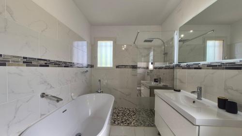 a white bathroom with a tub and a sink at La Santoline - Provençal break with pool in Le Thor