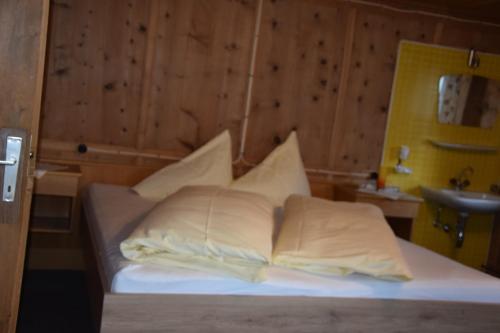 a bed with white sheets and pillows in a room at Haus Sonnenhof in Kappl