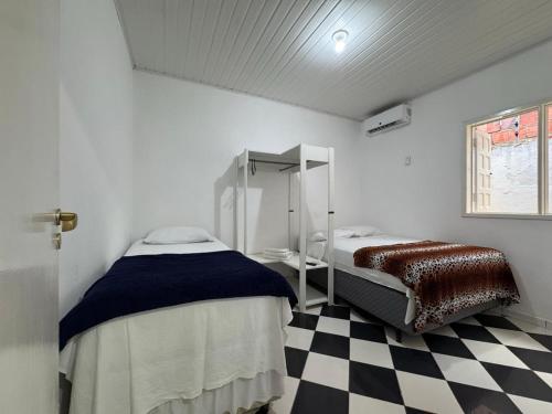 a bedroom with two beds and a checkered floor at Flat Jubarte Praia do Francês in Marechal Deodoro