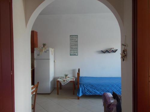 a room with a refrigerator and a table with a blue bed at Διαμέρισμα τριών ατόμων in Filiatra