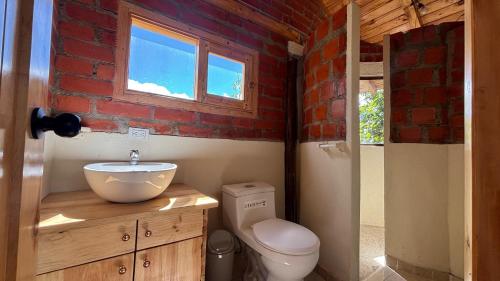 a bathroom with a toilet and a sink and a brick wall at El Tiklan Glamping in Chucchilán