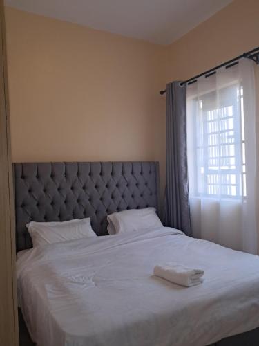 a bedroom with a large white bed with a window at Utele Cottages in Thika