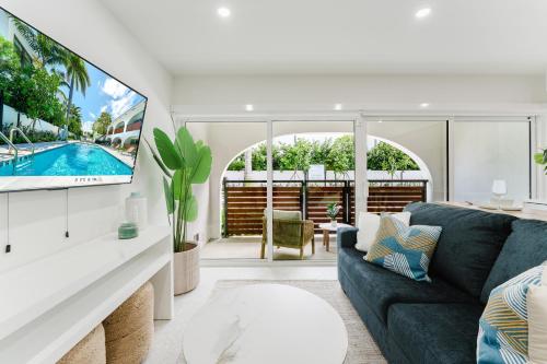 a living room with a blue couch and a tv at Villa Solana - Boca Pool Hideaway in Boca Raton