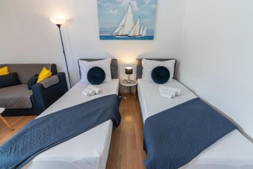 two beds in a room with a couch and a sailboat at Apartman Hana u blizini ronilačkog kluba i Kostrenskih plaža in Kostrena