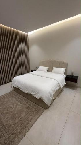 a bedroom with a large bed with white sheets at شقة انيقة بغرفة وصالة in Buraydah
