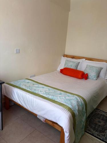 a bed with a red pillow on top of it at Tulivu House in Embu