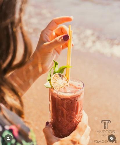 a woman holding up a drink with a lemon slice at Thanos Hotel in Muğla
