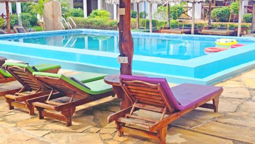 a group of chairs sitting next to a swimming pool at Mimi na wewe villa in Nungwi