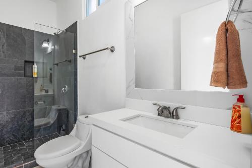 a white bathroom with a sink and a toilet at Dog-friendly Home with Partial Ocean View, Heated Pool, Rooftop Terrace in Rosarito