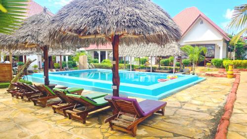 a pool with a bunch of chairs and umbrellas at Mimi na wewe villa in Nungwi