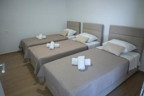 three beds with white pillows on them in a room at Villa La Lana in Mostar
