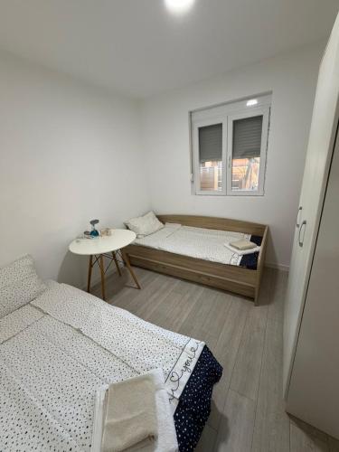 a bedroom with two beds and a table and a window at Home Two Brothers in Bar