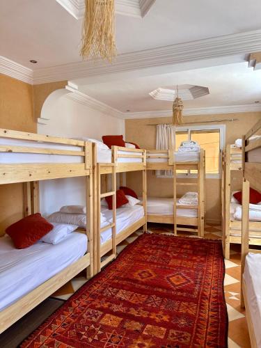 a room with four bunk beds and a rug at Tiri Hub in Tamraght Ouzdar