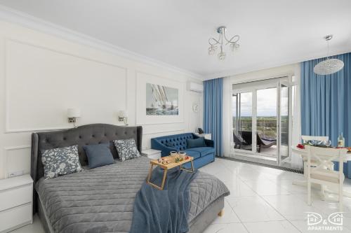 a bedroom with a bed and a blue couch at Marítimo D&D Apartments Porta Mare in Dziwnówek