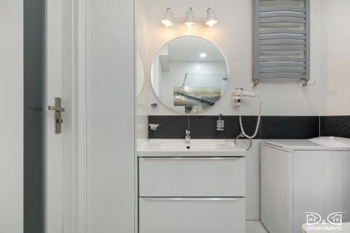 a bathroom with a white sink and a mirror at Marítimo D&D Apartments Porta Mare in Dziwnówek
