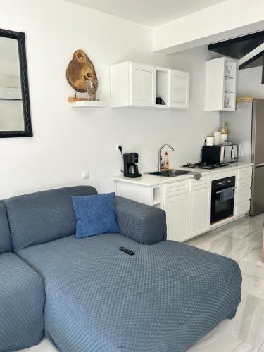 a living room with a blue couch and a kitchen at Coraçon di Mindel Apartment in Mindelo