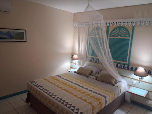 a bedroom with a bed with a canopy and two lamps at Charmant Studio CRISTAL COCO Les Trois-Îlets Martinique in Les Trois-Îlets