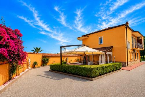 an orange house with an umbrella and flowers at B&b Villa Romano in Salerno