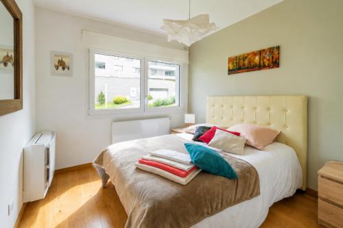 a bedroom with a large bed with pillows on it at Lac arte postale- Terrasse, grand garage privatif, borne de recharge en électricité, climatisation murale un appareil dans chaque pièce et unité extérieure, lit-parapluie pour bébé possible in Annecy