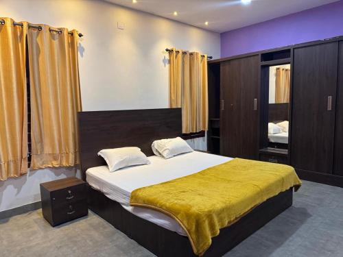 a bedroom with a large bed with a yellow blanket at Raintree Villa in Vythiri